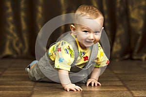 Childhood. Portrait of crawling baby boy on the bed curiously looking behind the camera