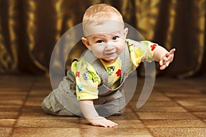 Childhood. Portrait of crawling baby boy on the bed curiously looking behind the camera