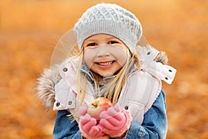 Portrait of happy little girl with apple in autumn