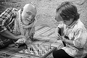 Childhood. Senior man teaching his grandson to play chess. Kid Playing Chess. Grandfather and grandson concept.