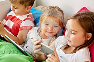 Little kids with smartphone in bed at home