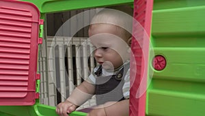 Childhood, toddler, motherhood, summer. Happy smiling Baby Boy Kid playing hide-and-seek and looks out the window in