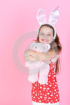 Childhood, youth and growth Happy girl hugging rabbit toy on pink background.