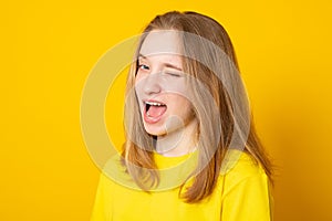 Childish and playful teenage girl winking at camera, keeping mouth wide opened