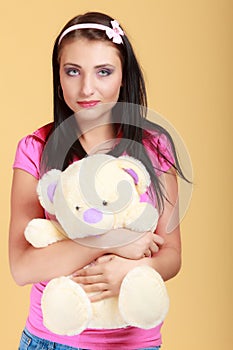 Childish young woman infantile girl in pink hugging teddy bear toy