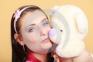 Childish young woman infantile girl in pink kissing teddy bear toy