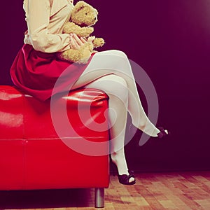 Childlike woman and teddy bear sitting on couch