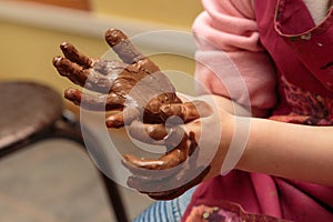 Childre hands are smeared by clay