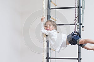 Children Activity Concepts. Little Caucasian Girl Having Exercises on Wall Bars Indoors.