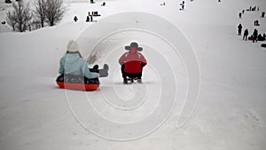 Children and adults alike are listed on the ice slide on inflatable rings. sledges, plastic skating rinks