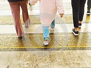 Children and adults cross the road on a pedestrian crossing on a cool day.