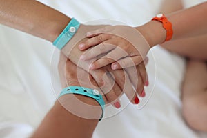 Children and adults` hands with bracelets are joined together.