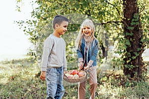 Children with Apple in Orchard. Harvest Concept. Garden, boy and blonde girl eating fruits at fall.