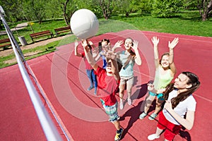 Children with arms up to ball play volleyball