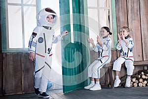 Children in astronaut costumes, girls applauding to boy