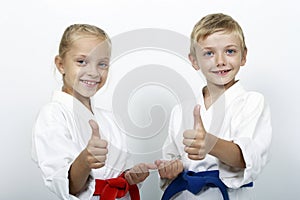 Children athletes with belts show a thumbs up