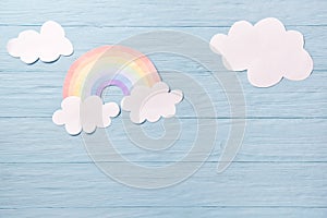 Children or baby background, white clouds with rainbow on the blue wooden background