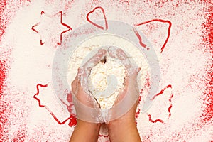 Children bake cookies for Christmas. Hands, star, tree, bell, heart, flour on a red background. Top view