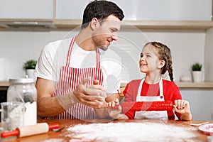 Children, baking, family concept. Cheerful brunet male wears apron and kneads dough, happy girl holds rolling pin, ready