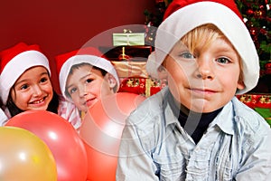 Children with ballons by Christmas tree