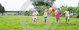 Children with balloons run in the summer park