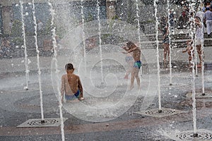 Children bathe in the fountain in summer day