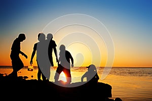 Children on the beach, fishing. Sunset shot, rear view. Sea background.