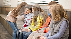 Children on a bench playing Chinese whispers