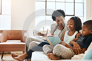 Children benefit the most from reading. a little brother and sister reading a book while their mother watches at home.