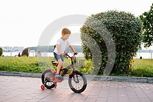 Children on a bicycle at asphalt road in early morning. Little boy learns to ride a bike in the park. Happy smiling child, riding
