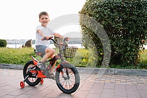 Children on a bicycle at asphalt road in early morning. Little boy learns to ride a bike in the park. Happy smiling child, riding