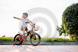 Children on a bicycle at asphalt road in early morning. Little boy learns to ride a bike in the park. Happy smiling child, riding