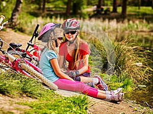 Children bicycle have rest near water in park outdoor.