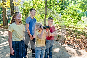 Children with binoculars on the road in the middle of the forest look ahead