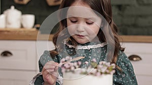 Children Birthday party at home. Adorable little child girl 4-5 years wears festive dress is eating with pleasure