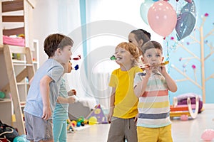 Children birthday party. Kids blow noisemaker horns photo