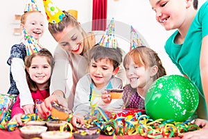 Children at birthday party with muffins and cake