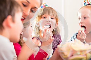 Children on birthday party nibbling candies