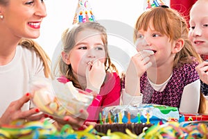 Children on birthday party nibbling candies