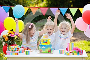 Children blow candles on birthday cake. Kids party
