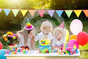 Children blow candles on birthday cake. Kids party photo