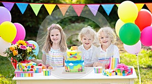 Children blow candles on birthday cake. Kids party