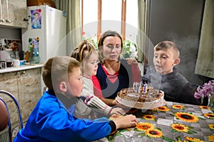 Children blow out candles on a name cake, a delicious dessert for a birthday, bright and colorful candles