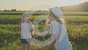 Children blowing soap bubbles, two girls playing in nature