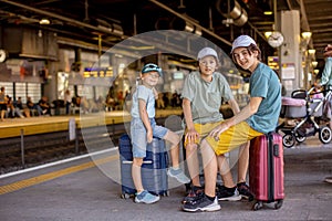 Children, boy brothers holding suitcases, travelin, waiting at trainstation to go to the airport photo