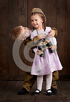 Children boy are dressed as soldier in retro military uniforms and girl in pink dress