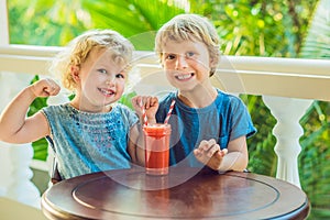 Children boy and girl drink orange smoothie from papaya