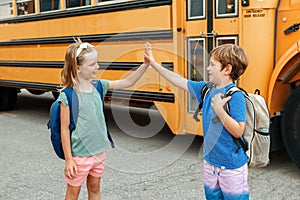 Children boy and girl kids students give hands high five by yellow school bus. Education and back to school in September. Friends