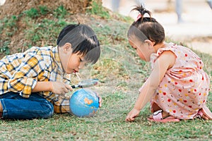 Children boy and girl looking at globe for learning