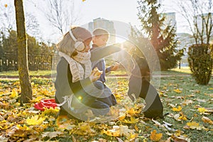 Children boy and girl playing with dachshund dog in a sunny autumn park